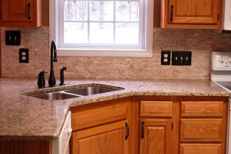 Beige stone backsplash between wooden kitchen cabinets