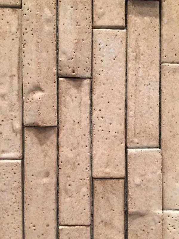 Narrow beige ceramic wall tiles laid in vertical rows