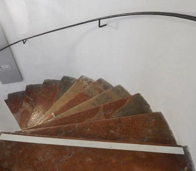Curved staircase with reddish-brown stone treads