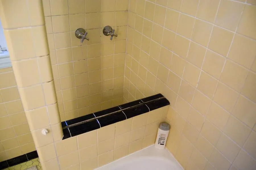 Bathroom with yellow wall tiles and a black horizontal border