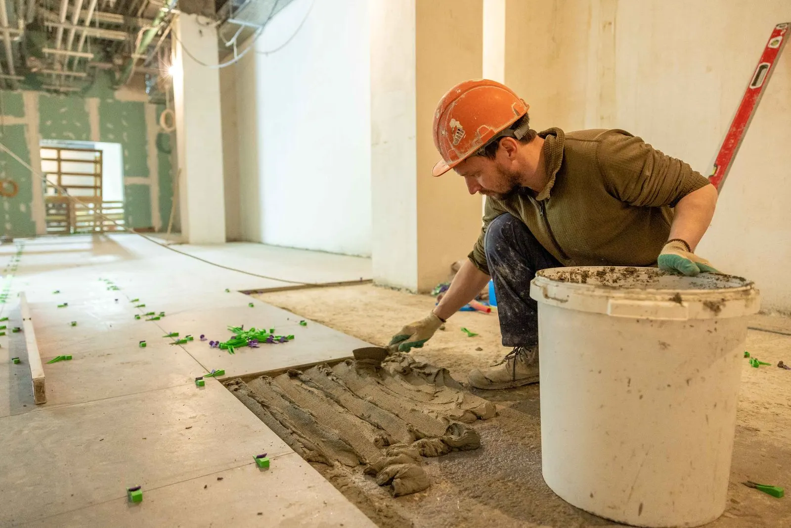 Tiler carefully setting and levelling a large-format floor tile on site
