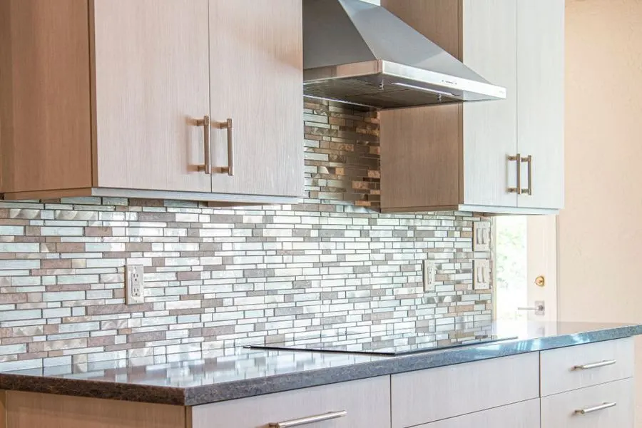 Glass and stone mosaic kitchen backsplash beneath an extractor hood