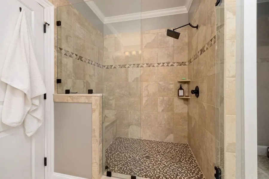 Walk-in shower with beige stone tiles and a pebble-style floor