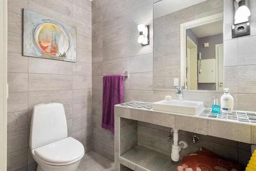 Bathroom vanity with pale rectangular stone-pattern wall tiles