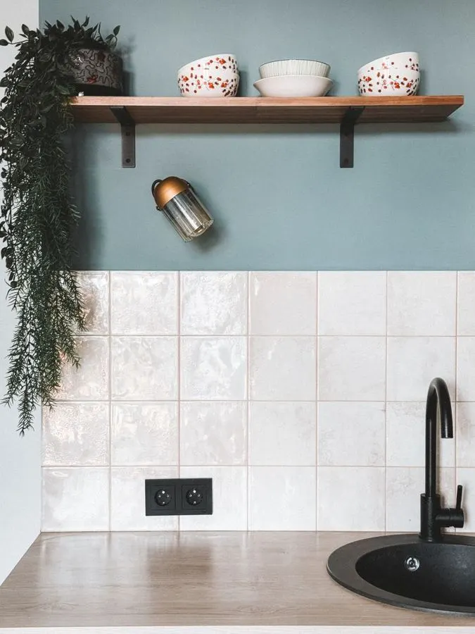 White kitchen backsplash with black fittings and open shelves