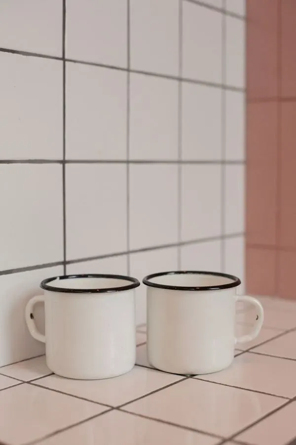 White square kitchen tiles with two enamel mugs on the counter