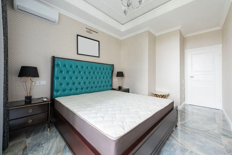 Bedroom with a teal headboard and grey marble-pattern floor