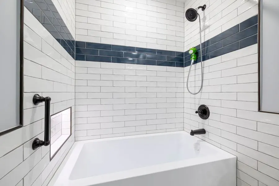 White tiled bathtub surround with a dark blue border